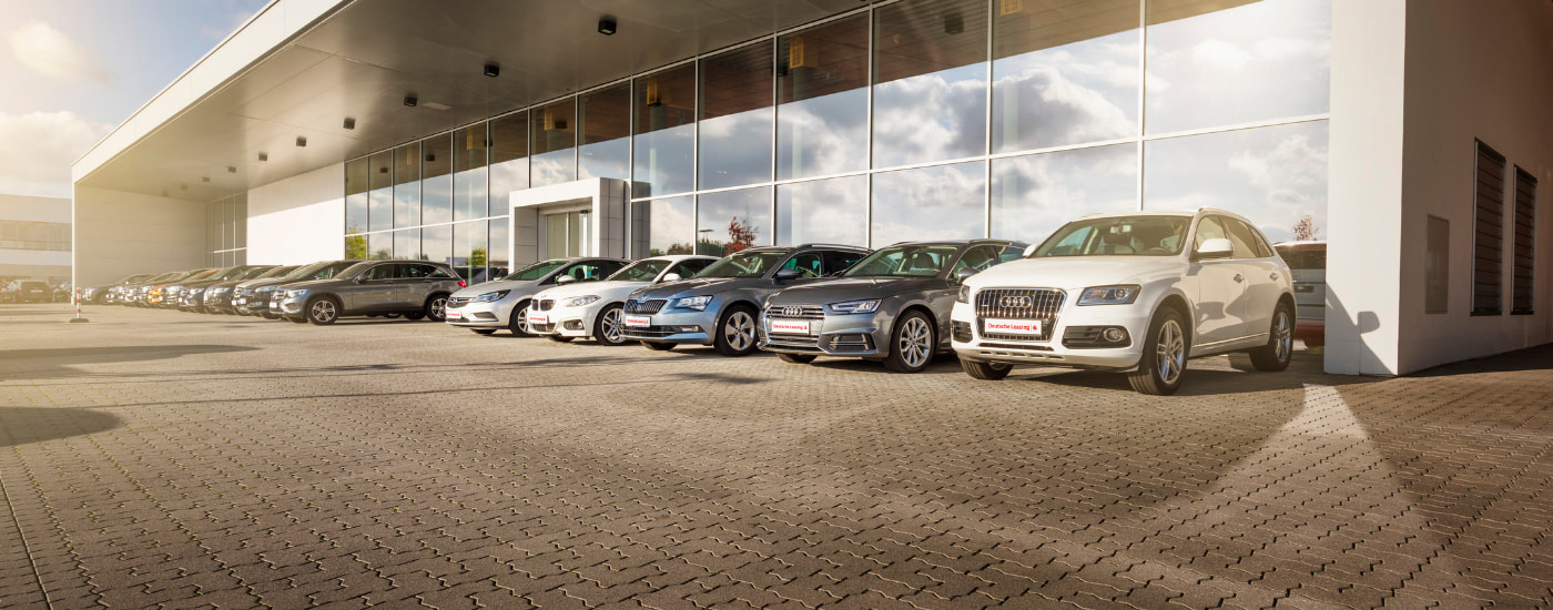 Mobilitätslösungen: Der umfassende Blick auf Ihre Flotte Verschiedene Autos stehen vor einem Glasgebäude